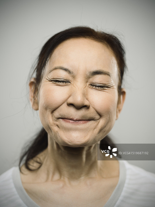 一个快乐的日本老年妇女闭着眼睛的肖像。图片素材