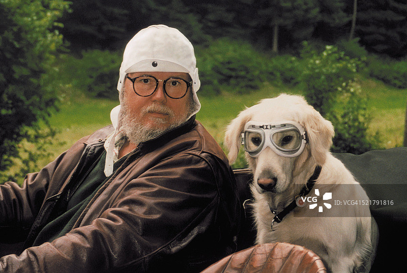 年长男性司机在古董车与宠物狗乘客戴着安全护目镜图片素材