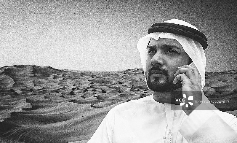 阿拉伯酋长在沙漠里打电话图片素材