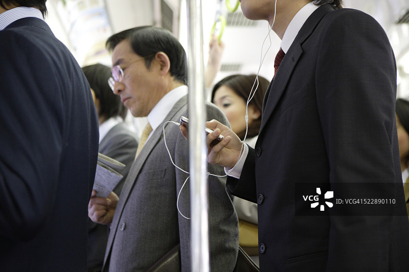 一名男子在拥挤的火车上听MP3图片素材