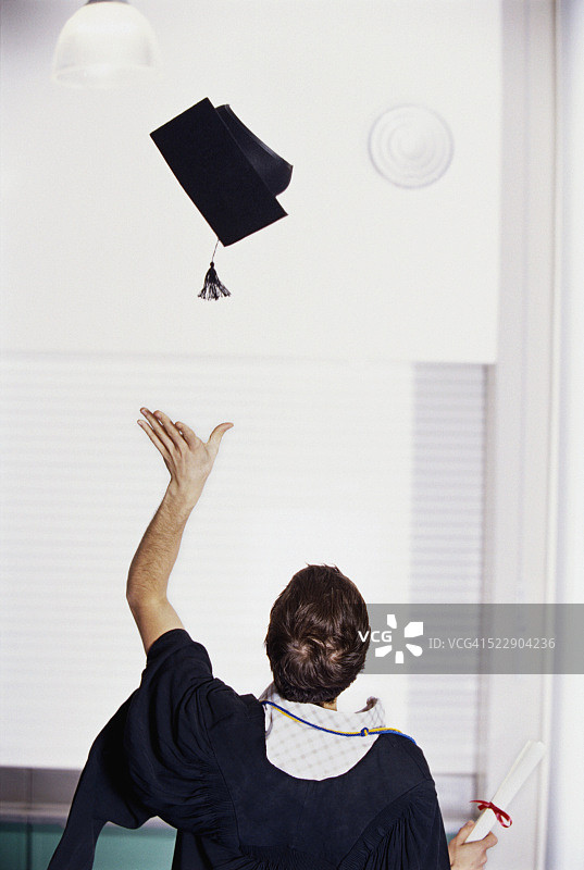 一个女人把她的毕业帽扔向空中的后视图图片素材