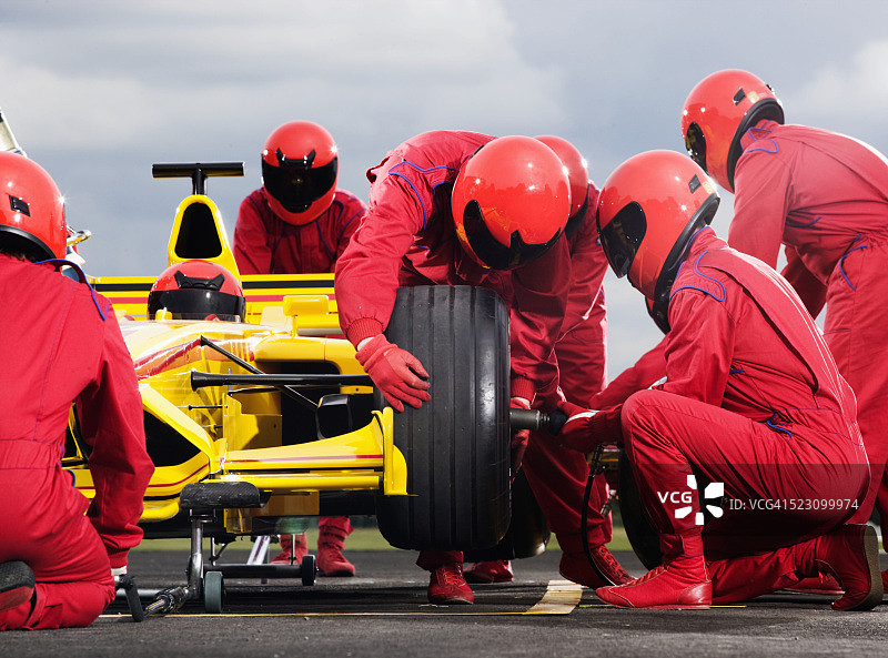 维修站工作人员在赛车上更换轮胎图片素材
