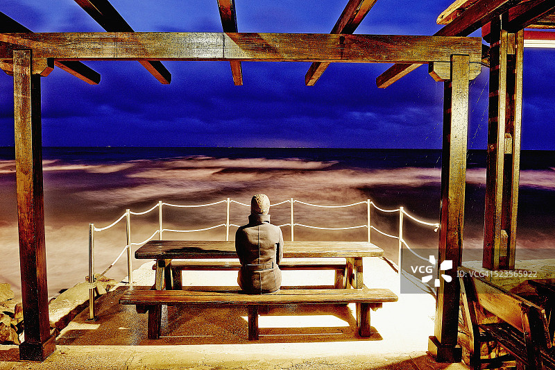 后视图的女人坐在海滩上，塔里法，加的斯省，安达卢西亚，西班牙图片素材