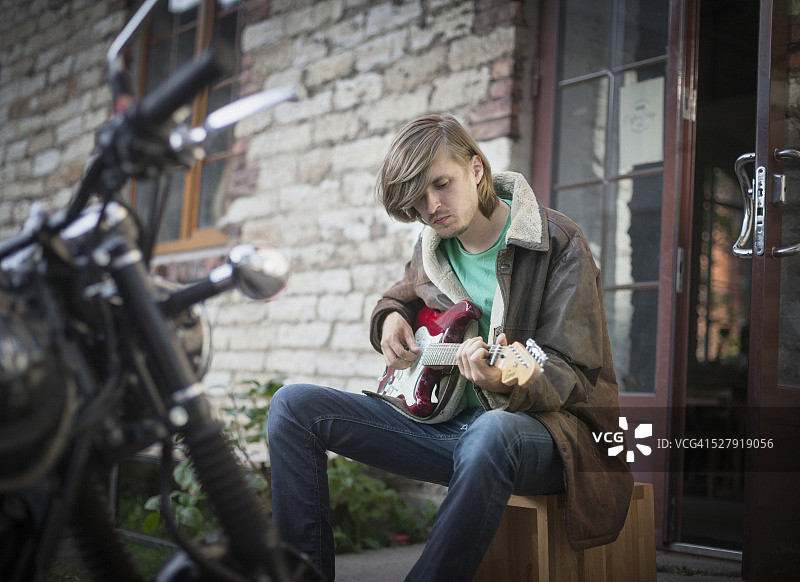 一个年轻人在石头建筑前弹吉他图片素材