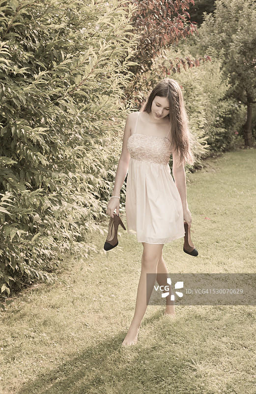 一个年轻女子赤脚走在花园里的草地上图片素材