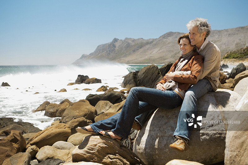 一对夫妇坐在海滩的岩石上图片素材