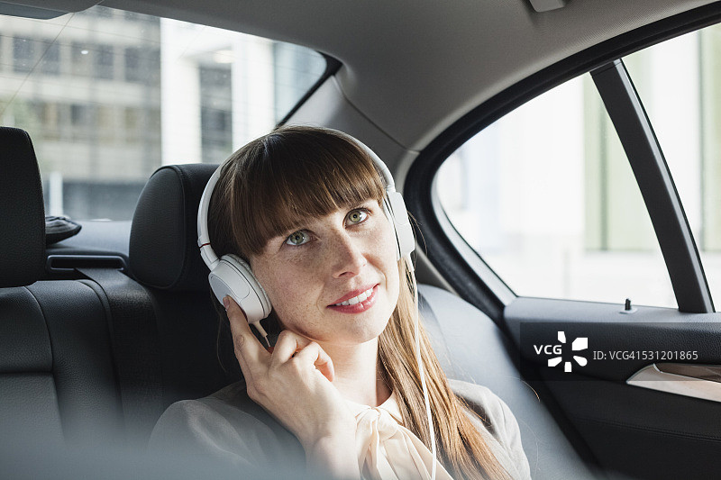 带着耳机的微笑女商人在她的车里听音乐的肖像图片素材