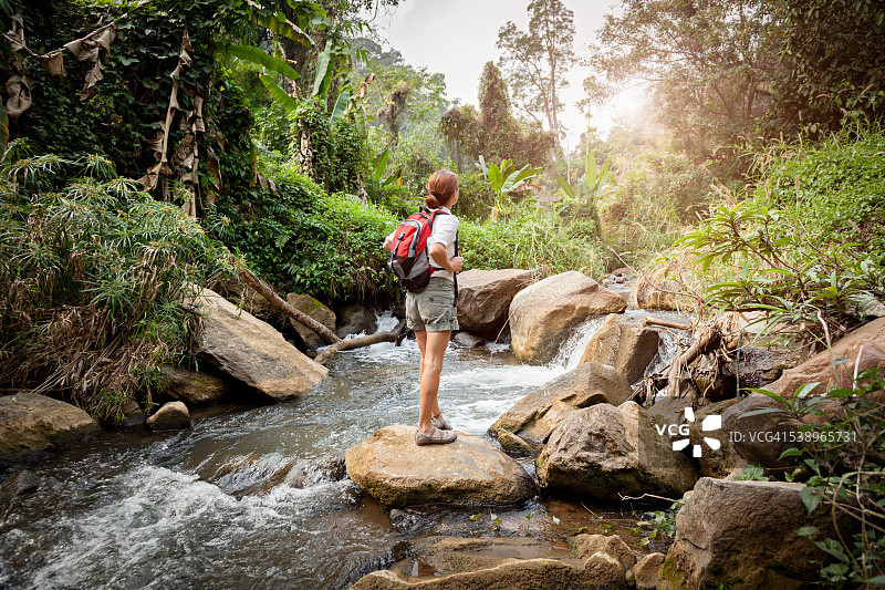 背着背包在雨林河徒步旅行的女人图片素材