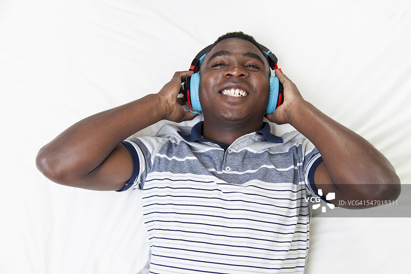 南非开普敦，一个年轻的非洲少年躺在床上，听着音乐图片素材