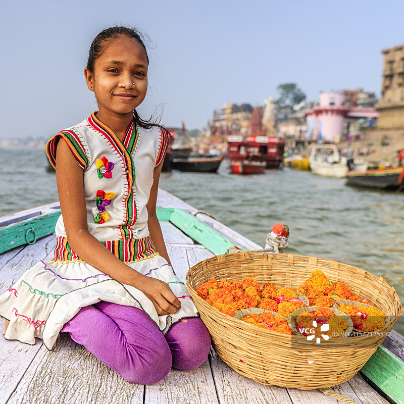 瓦拉纳西恒河上，小女孩在船上卖花蜡烛图片素材