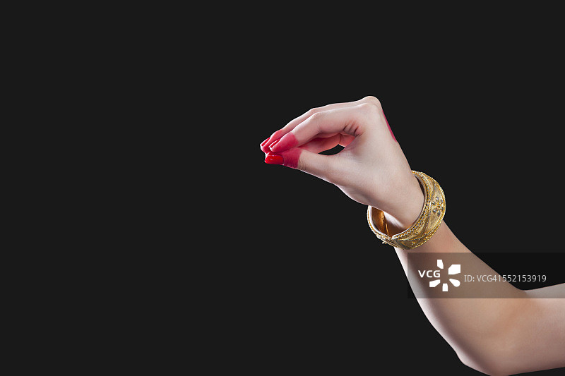 一个女人的手在黑色背景上做了一个叫做穆库拉的手势的特写图片素材