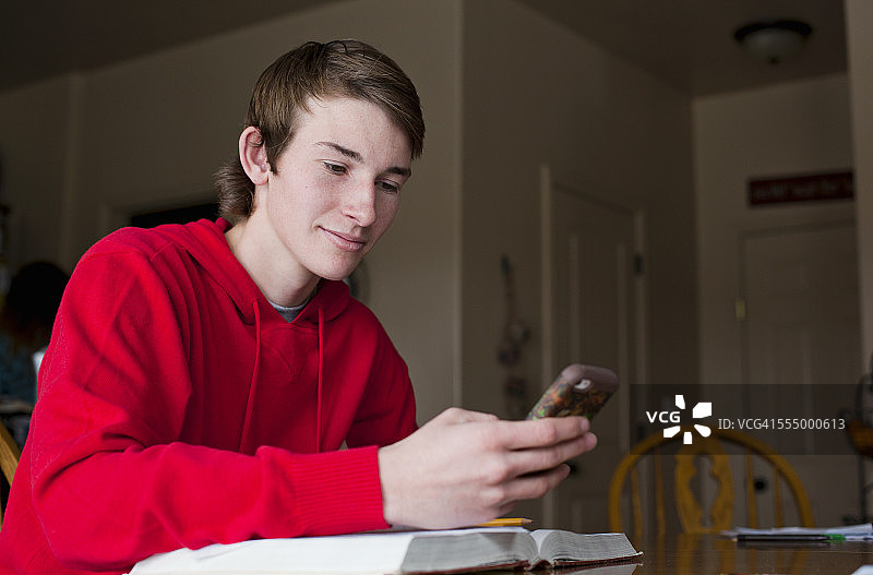 十几岁的男孩在餐桌上看手机图片素材