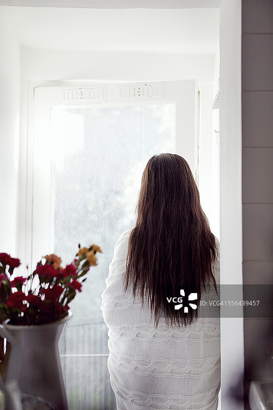 裹着毯子的女人站在窗前望着窗外图片素材