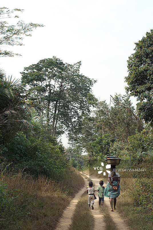 利比里亚的一名妇女和她的孩子步行去农场。图片素材