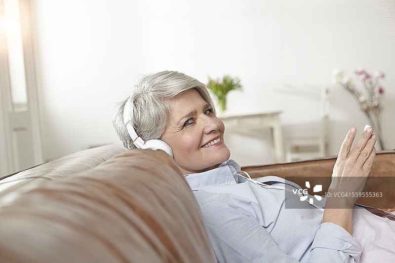 成熟的女人坐在沙发上听音乐图片素材