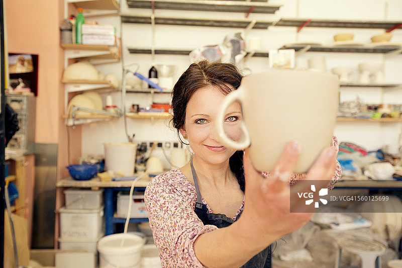 肖像微笑的陶工在工作室拿着水壶图片素材