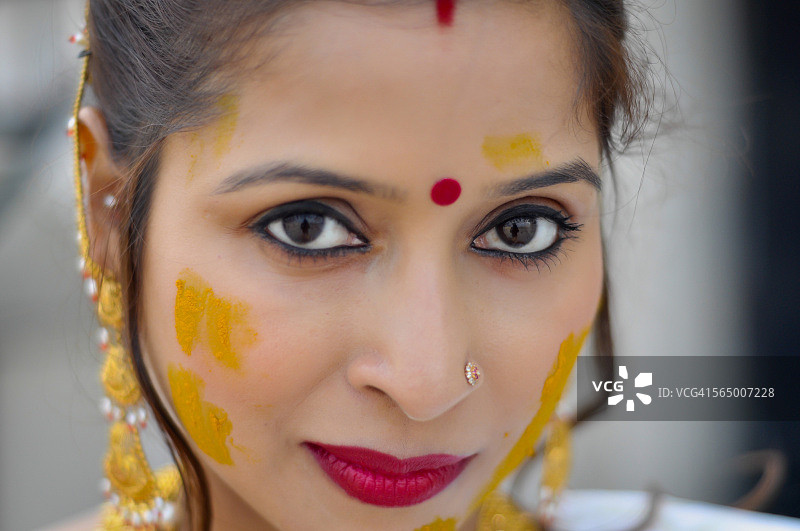 一个年轻的印度妇女与金饰和姜黄也被称为哈尔迪的特写图片素材