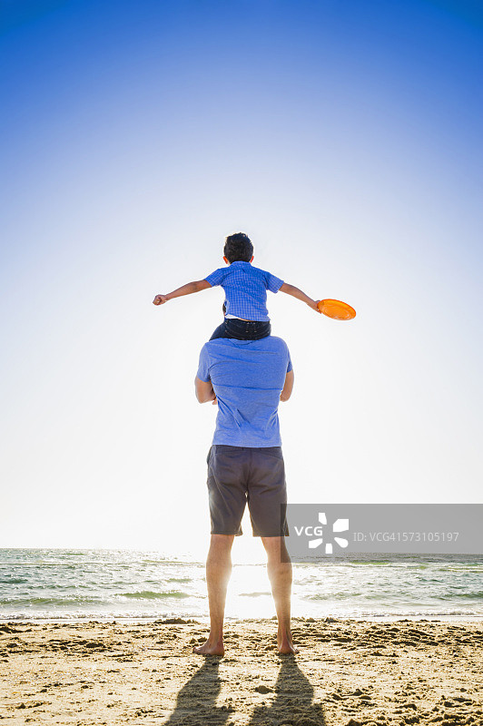 一个白人父亲背着儿子在海滩上图片素材