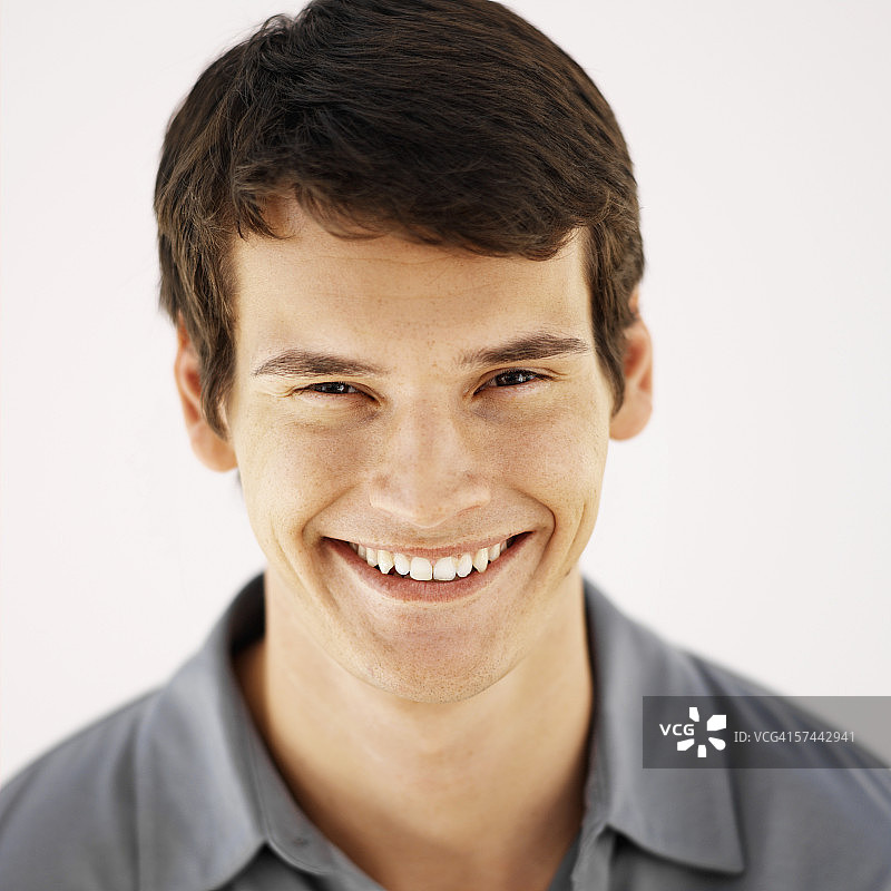 一个穿着灰色衬衫微笑的年轻人的肖像图片素材