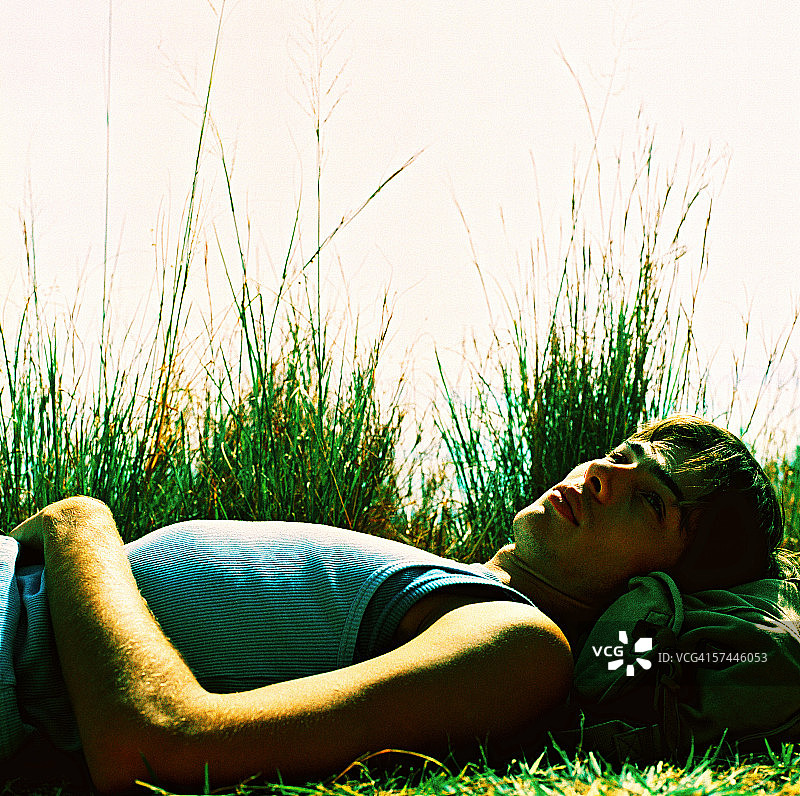 一个年轻人躺在草地上的低角度视图图片素材