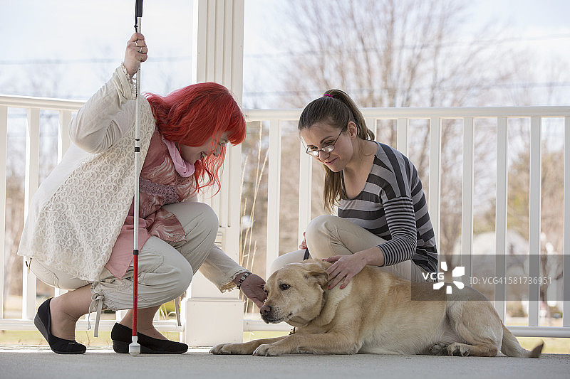 两个有视力障碍的女人，一个带着服务犬，一个拄着拐杖图片素材