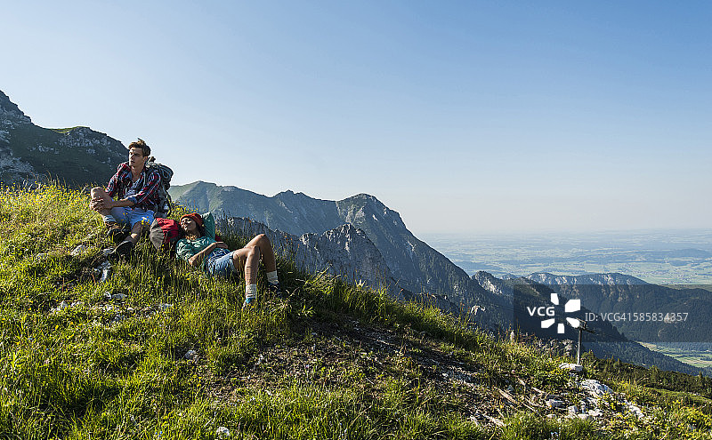奥地利，蒂罗尔，坦海默·塔尔，一对年轻夫妇在高山草地上休息图片素材