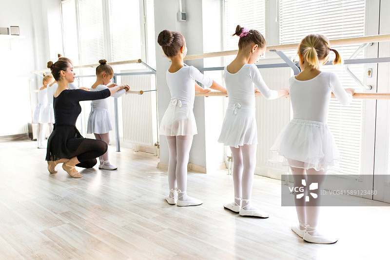 芭蕾舞老师在芭蕾课上帮助女孩们练习姿势。图片素材