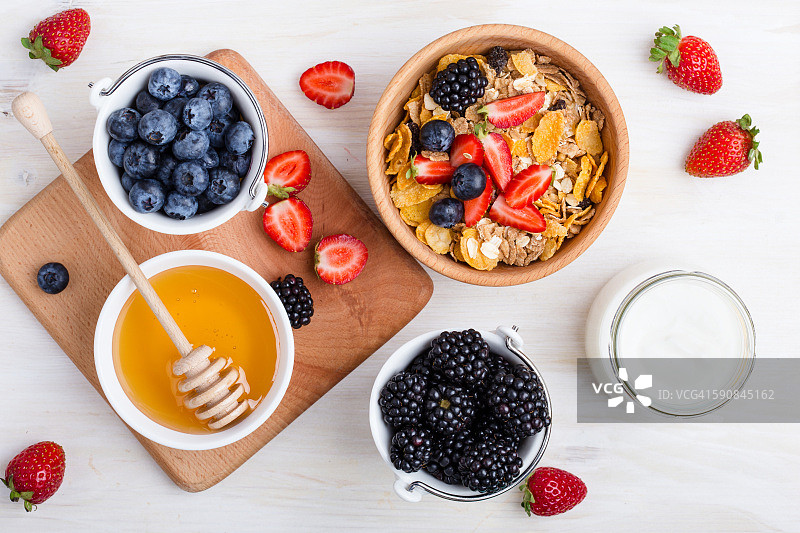 健康的早餐，麦片，新鲜的浆果，酸奶和蜂蜜，从上面俯瞰白色的木桌图片素材