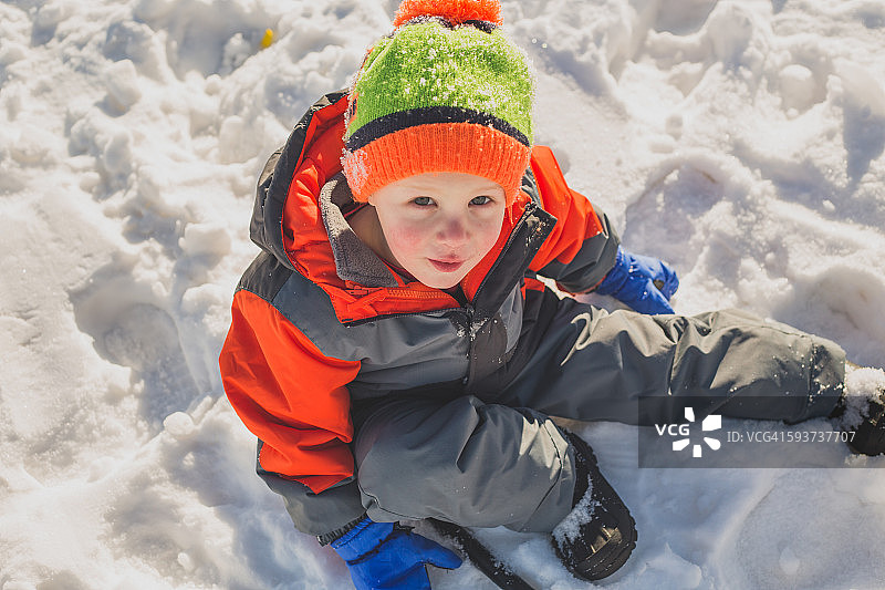 小男孩坐在雪里图片素材