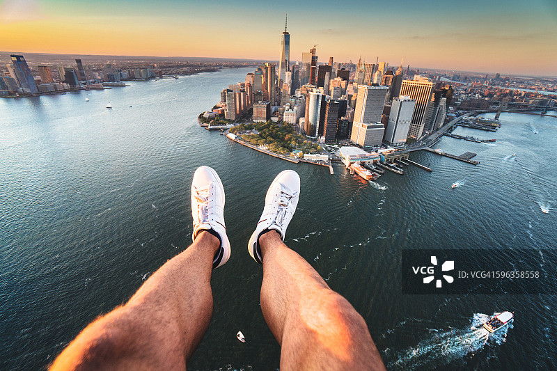 从直升机上拍摄的人类腿和曼哈顿天际线图片素材
