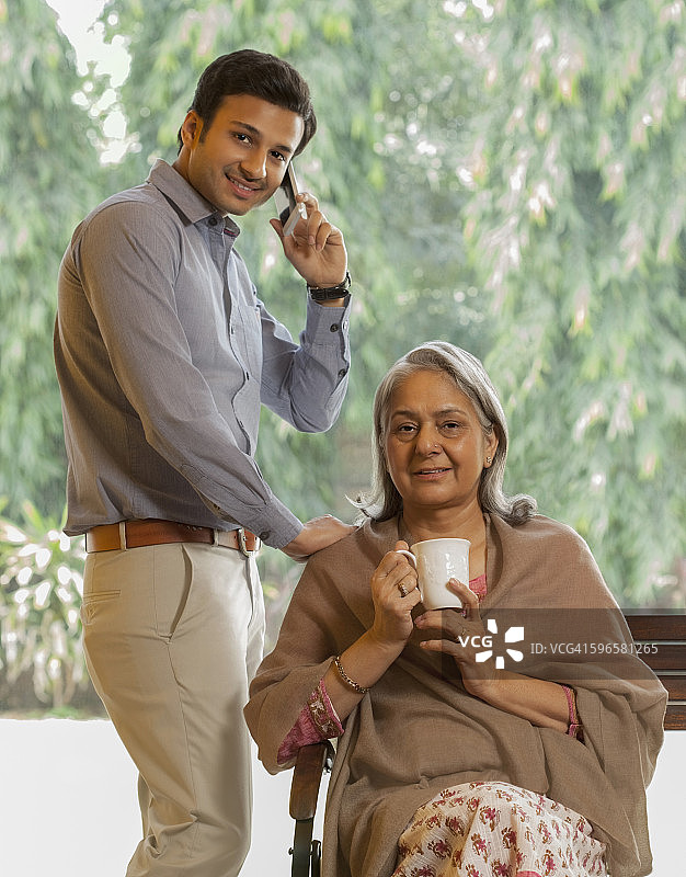 印度，在长凳上休息的老母亲旁边打电话的男人图片素材
