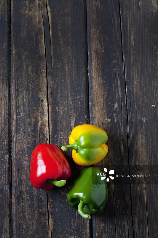 红色，黄色和绿色的甜椒在深色的木材上图片素材