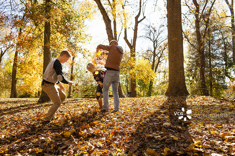 在秋天的森林里，一个年轻的女人和两个十几岁的兄弟在玩耍图片素材