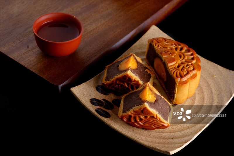 月饼和茶，中国中秋节的食品和饮料。传统月饼与茶壶的桌上摆设。图片素材