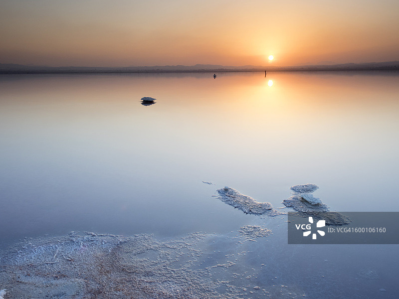 日落在一个盐湖，平静的水和橙色的天空和一个小岛图片素材