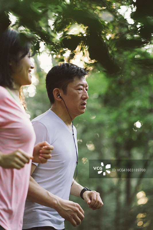 一对快乐的日本夫妇在户外的公园里跑步图片素材