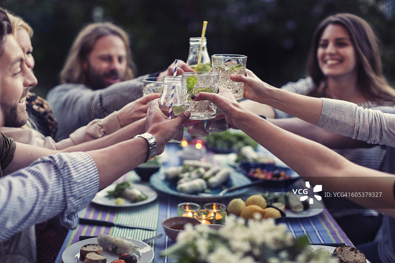 快乐的朋友们在院子里的餐桌上举杯畅饮图片素材