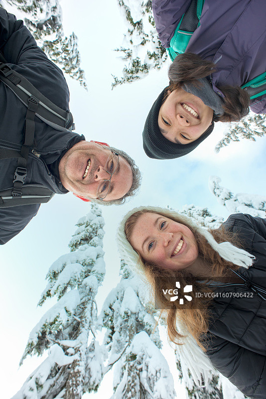 跨种族家庭和朋友向下看，雪覆盖的树背景图片素材