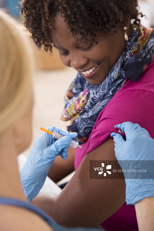 护士在诊所给病人注射流感疫苗。图片素材