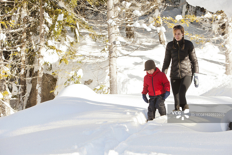 白人母亲和儿子踩着雪鞋走在路上图片素材