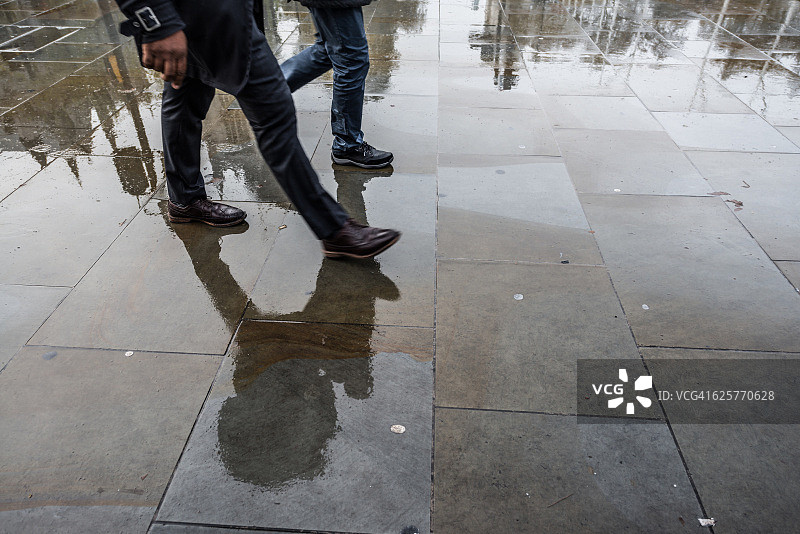 两名通勤者在潮湿的人行道上行走的下半部分，伦敦图片素材
