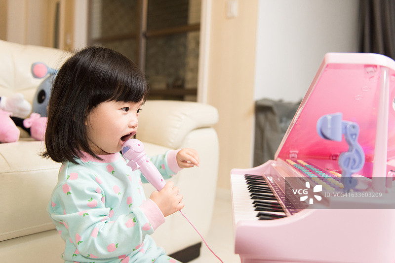 孩子在家里玩玩具钢琴，快乐地唱歌图片素材
