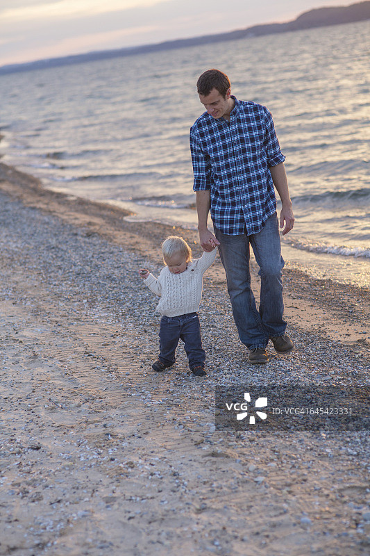 秋天，父亲在海滩上带着儿子散步图片素材
