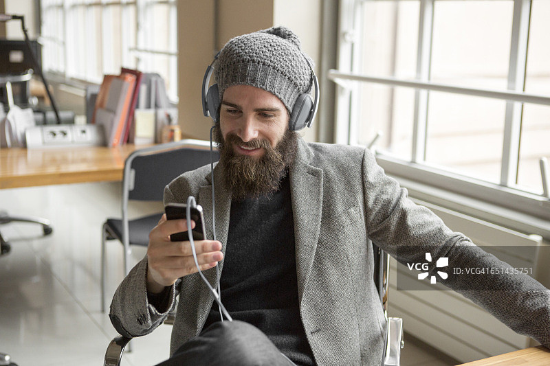 年轻商人的肖像戴着豆角帽使用智能手机图片素材
