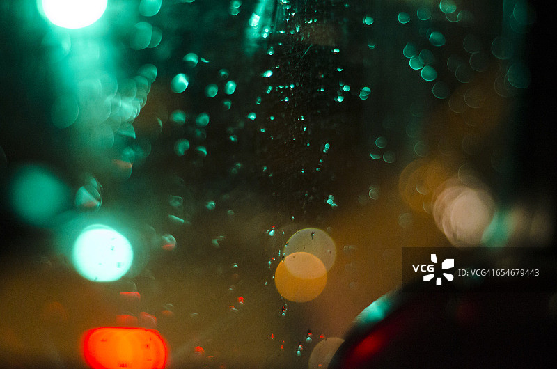 在南非豪登省约翰内斯堡的Joburg市中心，透过满是雨的巴士车窗，看到模糊的城市灯光。图片素材
