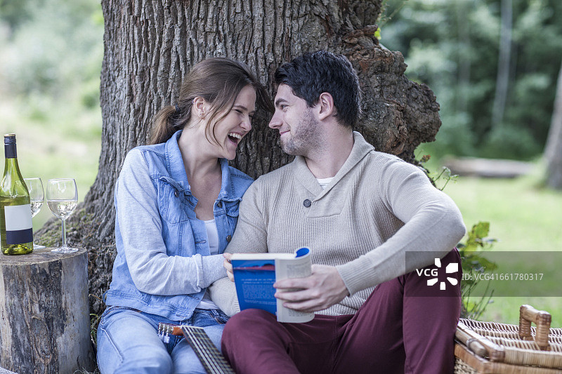 快乐的年轻夫妇正在用白葡萄酒野餐图片素材