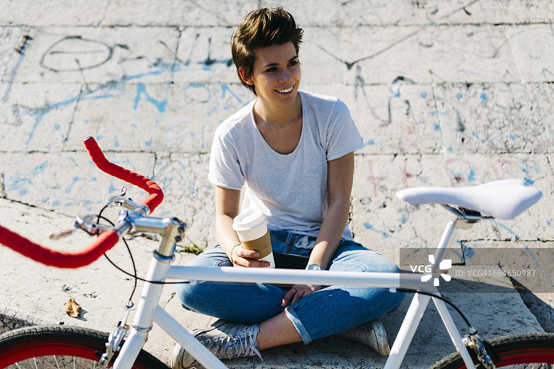 微笑的年轻女子，带着自行车和咖啡图片素材