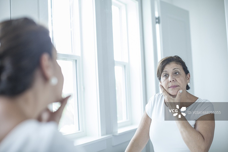 浴室里一个看着镜子的女人图片素材