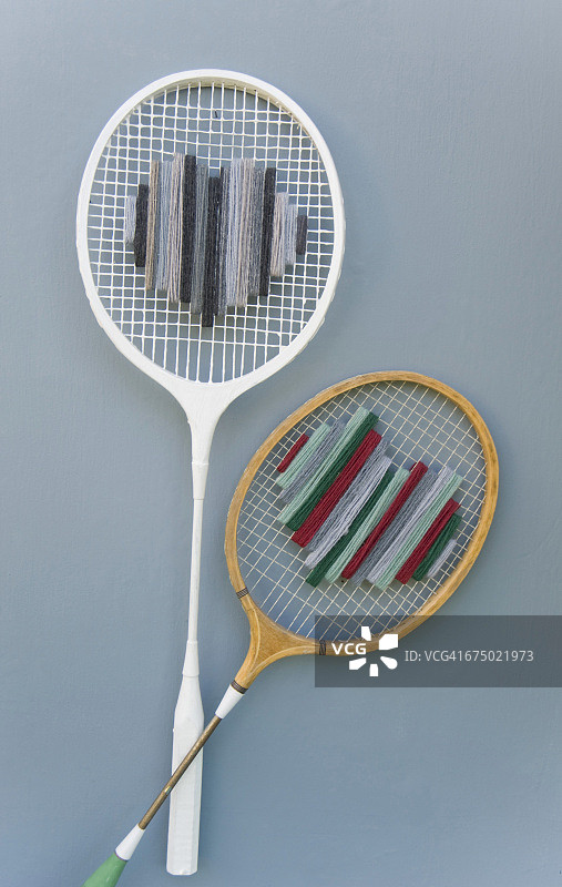 灰色的地面上放着两个旧的升级版羽毛球拍图片素材