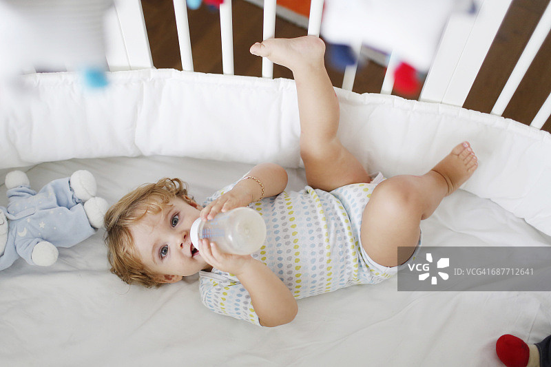 一个15个月大的男孩和他的婴儿床上的一个奶瓶图片素材